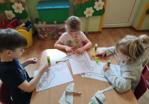 Dzieci wykonują pracę plastyczną "Dinozaur"